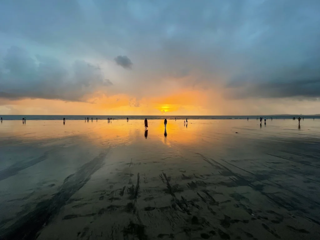 This image captures a serene sunset over the Arabian Sea at Juhu Beach in Mumbai, India. 