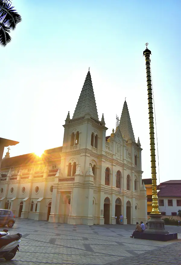 This image shows a scenic view of the Santa Cruz Cathedral Basilica in Fort Kochi, Kerala, during a sunset.