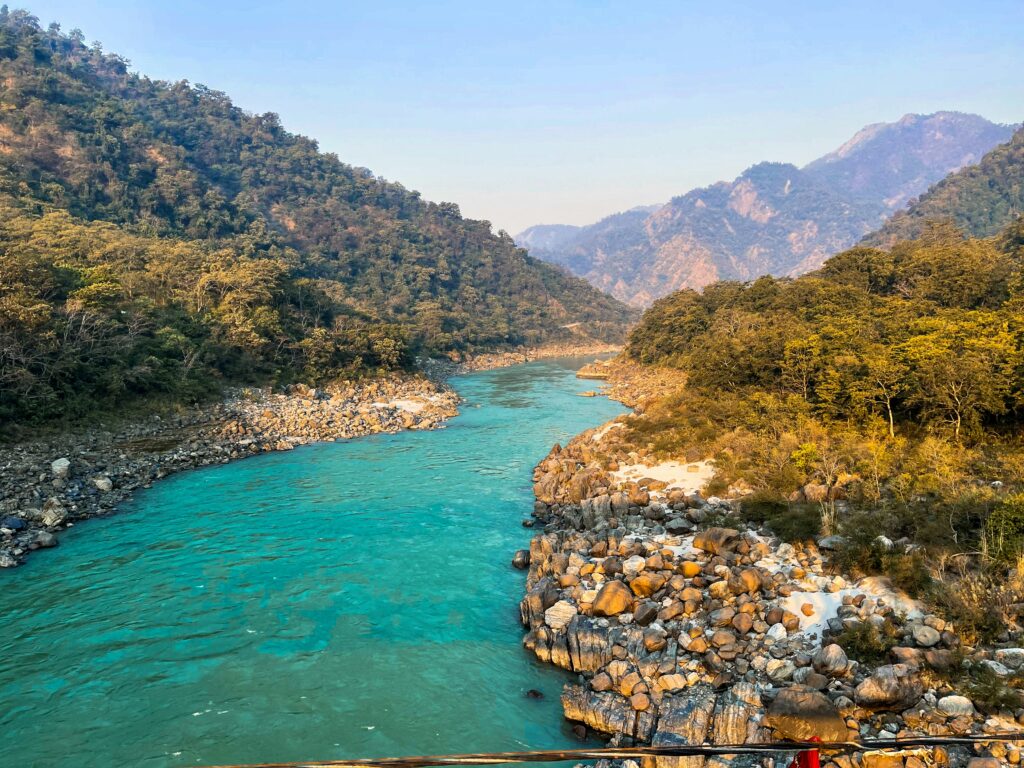 The sacred Ganges River flowing through a lush, mountainous landscape in Rishikesh.