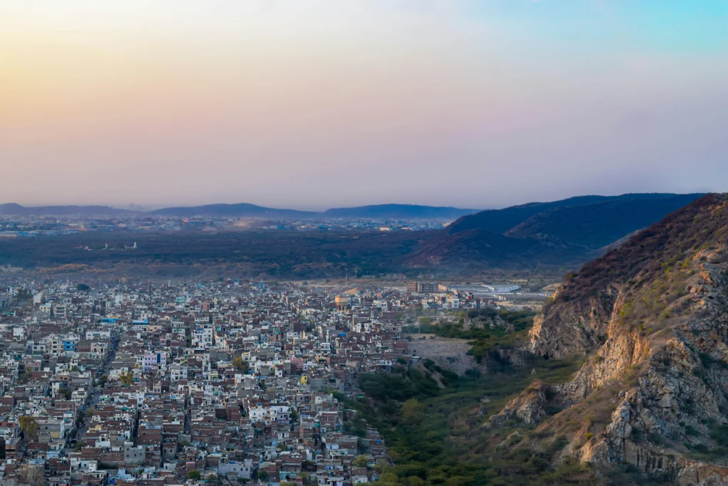 This photograph captures a sweeping view of Jaipur city from the vantage point of the Nahargarh Fort, set against the backdrop of the Aravalli Range.